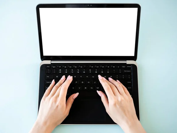 Digital mockup. Distance work. Modern technology. Female hands typing on laptop with blank screen isolated blue flat lay.