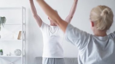 Kişisel fitness eğitimi. Yoga dersi. Spor terapisi. Gülümseyen orta yaşlı bir adam hafif iç mekanlarda kadın eğitmenle nefes egzersizinden zevk alıyor..