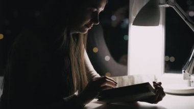 Gece okumaları. Geç saatlere kadar ders. Kitap kurdu. Akşam penceresinin önündeki karanlık odada edebiyatın keyfini çıkaran odaklanmış kadın öğrenci..