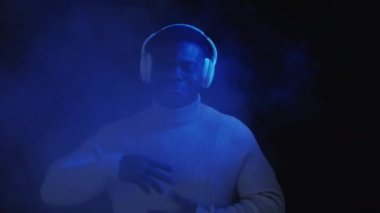 Neon ışığı müziği. Gece kulübü DJ 'i. Siber punk partisi. Kulaklık aleti. Neşeli, neşeli, dans eden adam disko dumanı efektiyle şarkı listesinden keyif alıyor..