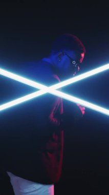 Dans döngüsü. Neon disko. Gece kulübü. Bumerang klipsi. Gif hareketli genç bir adam müziğin keyfini çıkarıyor. Parlak parlak ışıkta, karanlık stüdyoda dikey olarak..