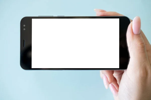 Mobile entertainment. Digital mockup. Online connection. Female hand holding smartphone with white blank screen isolated blue.