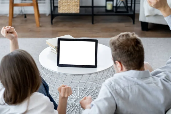 Online conference. Happy couple. Digital mockup. Unrecognizable excited man and woman sitting home looking tablet computer with blank screen in light room interior.