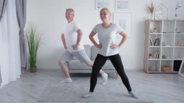 Aile eğitimi. Evde fitness. Aktif insanlar. Orta yaşlı, gülümseyen kızından esinlenerek bacakları güçlendirerek modern iç mekanlarda hareketlenmeyi seven bir baba..