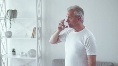 Sıvı diyeti. Sağlıklı bir yaşam tarzı. Sabah enerjisi. Mutlu, mutlu, orta yaşlı bir adam. Bardaktan maden suyu içiyor. Baş parmakla onaylıyor..