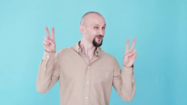Barış jesti. Zafer kutlaması. Bumerang animasyonu. Olumlu duygular. İyimser, mutlu, suratını buruşturan V işareti gif döngüsü gösteren komik adam mavi boş alan arka planında izole edilmiş..