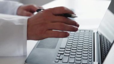 Elektronik tıbbi kayıt. Çevrimiçi sağlık hizmeti. Hastane acil servisi. Erkek doktor dizüstü bilgisayarla yazı yazıyor. İş yerinde not alıyor..