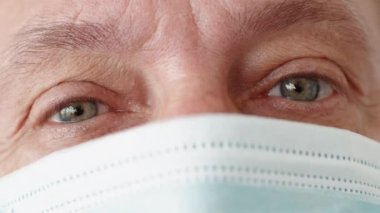 Pandemik depresyon. Coronavirus karantinası. Sempati duygusu. Medikal maskeli, üzgün gözlü, endişeli, orta yaşlı bir adamın yakın çekimi..