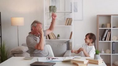 Eğlenceli evde öğrenme. Aile eğlencesi. Ders arası. Heyecanlı baba küçük kız ev ödevini modern iş yerinde beşlik çakarak kutluyor..