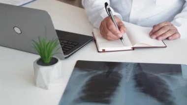 Akciğer muayenesi. Teşhis radyolojisi. Tıbbi kayıtlar. Tanımlanamayan erkek doktor, iş yerinde not alarak göğüs röntgeni taraması yapıyor..