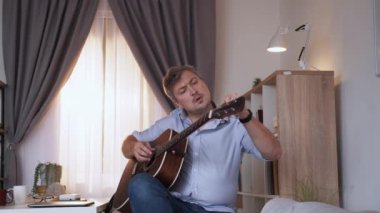İyi ses. Erkek oyuncu. Başarılı bir sonuç. Gitarı akort eden orta yaşlı bir adam aydınlık odada iyi bir uyum sağlamakla tatmin oluyor..