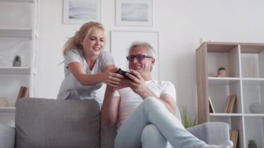 Aile eğlencesi. Video oyunu. Hafta sonu eğlencesi. Orta yaşlı babayı destekleyen heyecanlı kızı modern ev içinde kanepe üzerinde video oyunu oynuyor..