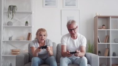 Video oyunu zaferi. Aile düellosu Ev eğlencesi. Hayal kırıklığına uğramış orta yaşlı baba, heyecanlı neşeli kızıyla oynarken kaybediyor..