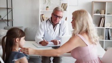 Çocuk sağlığı hizmetleri. Çocuk doktoru muayenesi. Çocuk kliniği danışmanlığı. Endişeli anne, modern iş yerindeki doktor randevusunda hasta küçük bir kız hasta ile birlikte..