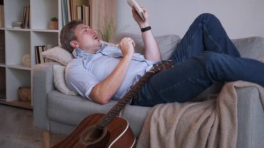 Müzik bestelemek. Erkek ozan. İlham perisi. Gündelik orta yaşlı bir adam, yanında gitarla kanepeye uzanmış, şarkı söylüyor, içerideki aydınlık odada deftere notlar yazıyor..