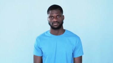 Jest gibi. Tatmin olmuş afro adam. Olumlu tepki. Mükemmel seçim. Mutlu gülümseyen Afrikalı adam, mavi fotokopi arkaplanında izole edilmiş destek levhasıyla cesaret veriyor..