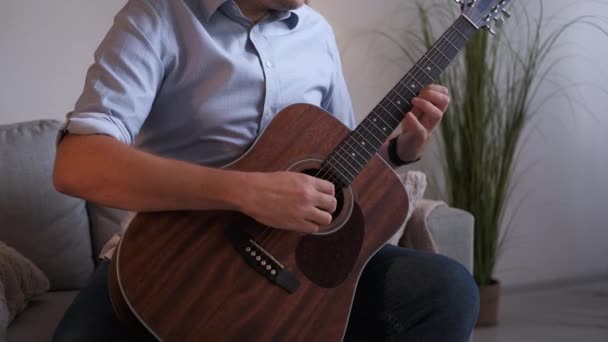 音乐的灵感男作曲家 音响效果坐在沙发上 漫不经心地在室内弹吉他 难以辨认 — 图库视频影像