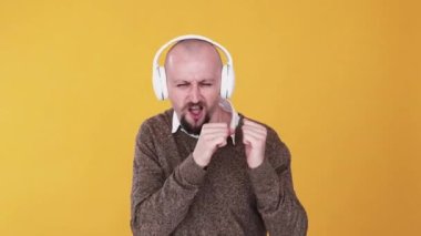 Müzik zevki. Eğlenceli bir ortam. Bumerang animasyonu. Mp3 uygulaması. Heyecanlı adam, turuncu fotokopi arka planında izole edilmiş kulaklıkla dans eden ve müzik dinleyen eğlenceli adam..