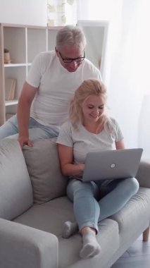 Aile çevrimiçi eğlence. Video oyunu. Sanal neşe. Neşeli orta yaşlı baba kazanan kız, zaferi kutluyor. Dizüstü bilgisayarda, hafif ev iç kısmında, dikey olarak oynuyor..