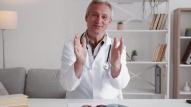 Tıbbi destek. TeleHealth toplantısı. Sanal check-up. Mutlu erkek doktor, modern iç mekanda başarılı iyileşme ve alkış ile hastayı selamlıyor..