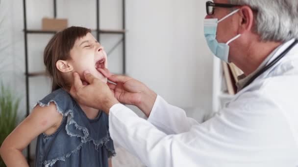 小児科医の訪問 子供の検査 呼吸器疾患 小児科 中年男性医師で保護顔マスク検査病気女の子患者喉の痛み — ストック動画