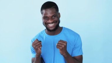 Tatmin olmuş Afrikalı adam. Zafer kutlaması. Evet, duygu. Olumlu tepki. Mutlu, heyecanlı, şaşkın, esmer tenli, gülümseyen adam mavi fotokopi alanında izole edilmiş..