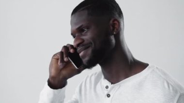 Cep telefonu bağlantısı. Telefon konuşması. Uluslararası iletişim. Dost canlısı, neşeli Afrikalı adam akıllı telefondan konuşuyor..