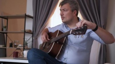 Enstrümantal ayar. Erkek oyuncu. Sesi ayarlıyorum. Elinde gitarla gezen orta yaşlı bir adam ışık odasının içindeki tellerin başlığını çeviriyor..