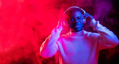 Neon ışığı müziği. Gece kulübü DJ 'i. Siber punk partisi. Kulaklık pankartı. Mutlu kaygısız adam kırmızı dumanlı arka planda tekno çalma listesinden keyif alıyor..