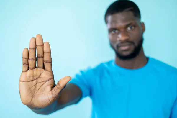 Stop hand. No gesture. Risk prevention. Black lives matter. Rejecting serious man outstretched palm in refusal sign isolated on blue studio background.