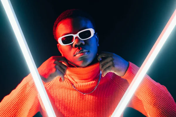 Siberpunk portresi. Havalı adam. Fütürist bir gece. Şık giyinmiş, ciddi bir adam. Güneş gözlüklü. Koyu arkaplan ışıklı..