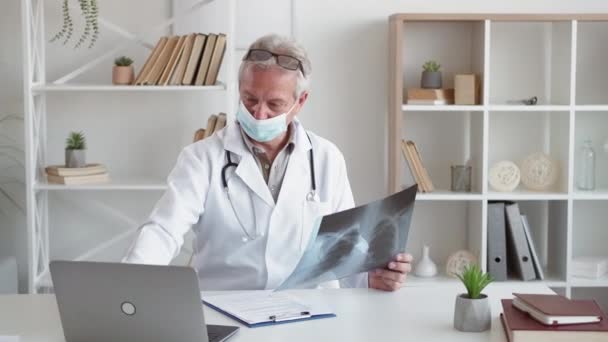 肺放射科呼吸系统感染 珊瑚病毒感染 中年男子医生戴口罩 研究现代诊所室内胸部X光扫描 — 图库视频影像