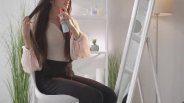 Saç stili kozmetik. Kadın güzelliği. Termal koruma. Tanınmayacak kadar güzel bir kadın. Pürüzsüz, uzun, esmer saçları var. Işıklı odada oturuyor..