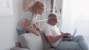 Baba video oyunu. Çevrimiçi zafer. Aile eğlencesi. Heyecanlı kız fanatiği orta yaşlı kazananı destekliyor. Baba dizüstü bilgisayarda oynuyor..