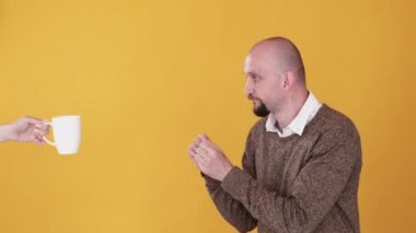 Kahve sever. Kafein bağımlılığı. Sabah içkisi. Bumerang animasyonu. Kafayı takmış bir adam, kadın kahvecinin ellerine uzanmış portakal renkli fotokopi arka planında izole edilmiş gif döngüsü..