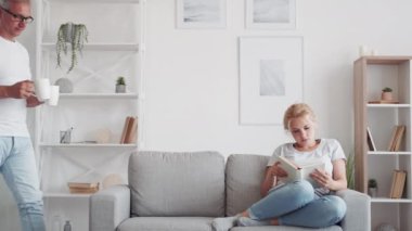 Aile kahve molası. Hafta sonu tatili. Orta yaşlı bir baba, modern oturma odasındaki kanepede kitap okuyarak kızına sıcak içecek servisi yapıyor..