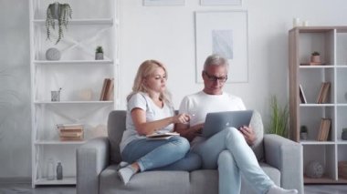 Aile çalışması. Çevrimiçi araştırma. Evde eğitim. Akıllı kız orta yaşlı baba modern oturma odasındaki koltukta dizüstü bilgisayar kullanıyor..