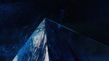 Mürekkep arkaplanı. Renk sıvısı sıçraması. Buz Tepesi. Lacivert duman sisi şeffaf cam piramidin üstünde koyu siyah bokeh açık renk dokuda..