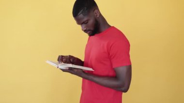 Yorgun Afrikalı öğrenci. Eğitim stresi. Yorgunluğu öğreniyorum. Yorgun siyah adam kitap okuyor sınava hazırlanıyor. Avuç içi jesti sarı boş arkaplanda..