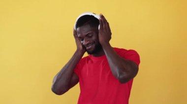 Müzik serinliği. Ses meditasyonu. Zihin rahatlığı. Modern teknoloji. Huzurlu Afrikalı bir adam portakalsız alanda izole edilmiş kablosuz kulaklıklarla sakinleştirici ses ritmini dinlemekten zevk alıyor..