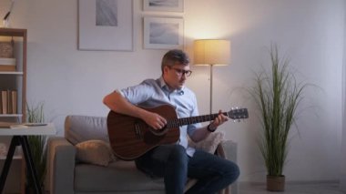 Müzik bestecisi. İlham verici bir adam. Evde eğitim. Yakışıklı, orta yaşlı, rahat bir adam. Kanepeye oturmuş gitar çalıyor. İç mekânda sakin duygular hissediyor..
