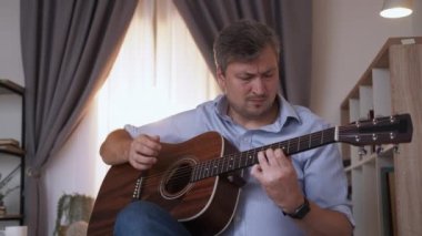 Müzikal hobi. Çaresiz adam. Öğrenme problemi. Hiçbir şeyden haberi olmayan orta yaşlı bir adam koltukta oturuyor ve iç mekanda gitar çalmakta zorlanıyor..