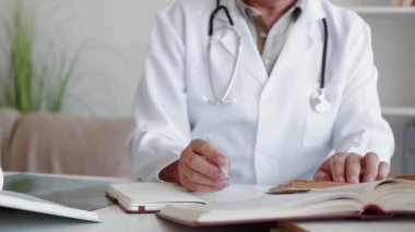 Doktor çalışması. Tıp bilimi. Profesyonel araştırma. Tanımlanamayan erkek hekim, kitap okuyarak modern iş yerinde notlar alıyor..