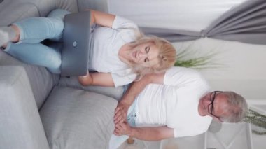 Video oyunu zaferi. İnternet aile eğlencesi. Hafta sonu eğlencesi. Heyecanlı orta yaşlı baba, modern ev içi dikey koltukta dizüstü bilgisayar kullanarak kazanan kızı destekliyor..