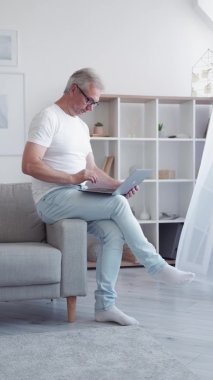Dijital çalışma. Sosyal medya blogu. İnternet iletişimi. Hafif modern ev içi dikey dizüstü bilgisayar kullanarak içeriği yazan zeki, orta yaşlı bir adamdan esinlendim..