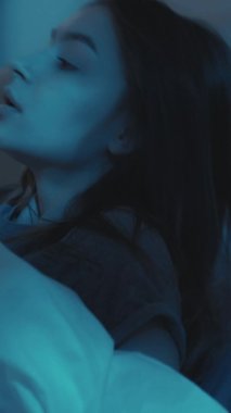 Yatak kâbusu. Uyku bozukluğu. Kötü bir rüya. Huzursuz, korkmuş bir kadın gecenin bir yarısı karanlık bir evde uyanıyor. Dikey video.