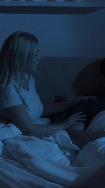 Gece çifti sorunu. Cinsel işlev bozukluğu. Destekleyici eş depresif, hayal kırıklığına uğramış üzgün koca, karanlık yatak odasında geç saatte yatakta. Dikey video.