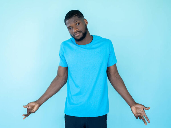 Clueless man. Shrug gesture. Difficult choice. Uncertain careless doubtful guy with unaware face isolated on blue studio background.