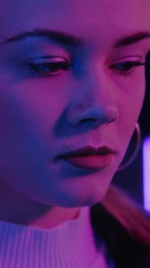 Üzgün kadın. Hayal kırıklığı. Neon ışıklı portre. Depresyondaki güzel bayan mor ışıklardan rahatsız oluyor. Dikey video.