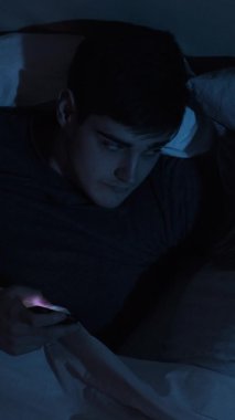 Mobil hile. İnternet ilişkisi. Sadakatsizlik ihaneti. Sadakatsiz sinsi koca gizlice konuşmak için telefonunu kullanıyor. Gece geç saatlerde uyuyan eşiyle yatakta uzanıyor. Dikey video.